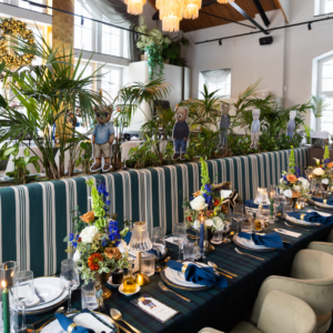 Navy blauwe servetten bruiloft tafelstyling Navy blauwe servetten op lange bruiloft tafel met goud bestek en kleurrijke bloemen