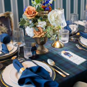 Navy blauwe servet op luxe gedekte tafel met goud bestek en bloemendecoratie