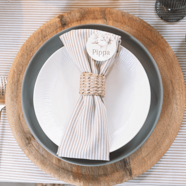 Rotan servetring met geplooid servet op bord – tafeldecoratie voor babyshower Rotan servetring met geplooid servet op bord – tafeldecoratie voor babyshower