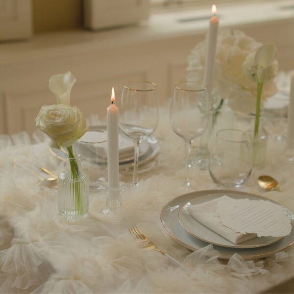 Glazen vaasjes in tafelstyling Overzicht van een zithoek met bloemen in glazen vaasjes en kaarsen op ronde tafels