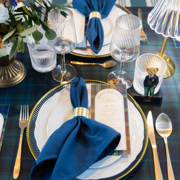 servetringen voor babyshower Gouden servetringen met blauwe servetten op gedekte tafel – elegante tafelstyling voor babyshower decoratie
