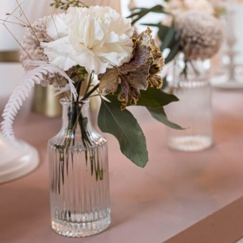 Bloemenvaasjes van helder glas tijdens babyshower met roze thema