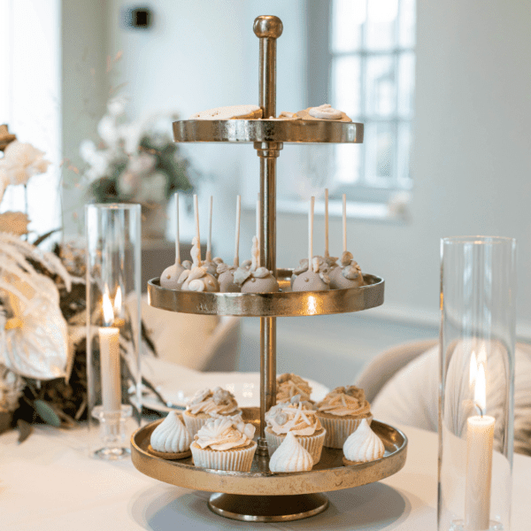 Dessert tafel met gouden etagère met 3 lagen Gouden etagère met 3 lagen met cupcakes op een romantische dessert tafel voor bruiloft of feest