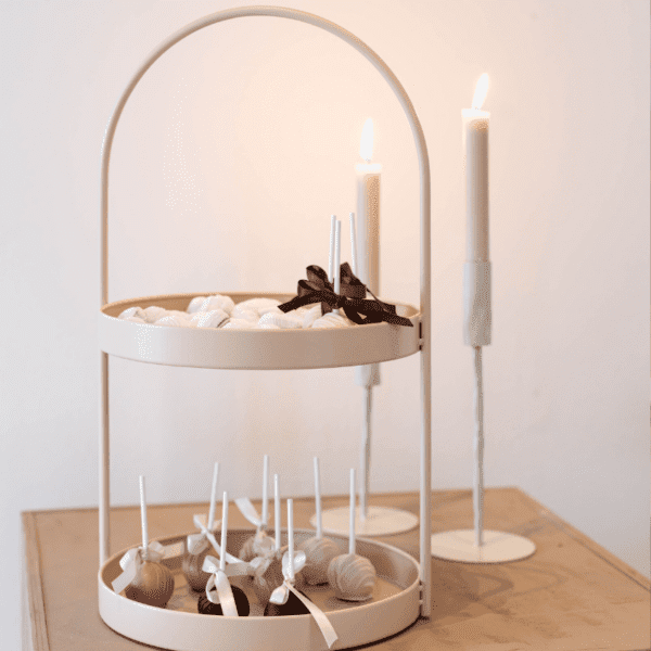 Roze serveerstandaard dessert presentatie Elegante roze serveerstandaard met twee lagen met desserts naast kaarsen op feestelijke tafel