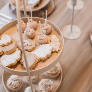 Zachtroze dessertstandaard met twee lagen met cupcakes en macarons op bruiloft sweet table