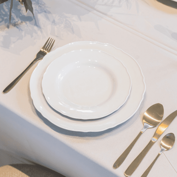 klassiek wit dinerbord tafelsetting klassiek wit dinerbord met romantische rand op gedekte tafel voor stijlvol diner