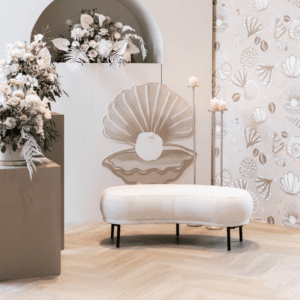 Elegant wit trouwbankje zonder leuning bij ceremonie backdrop met bloemen