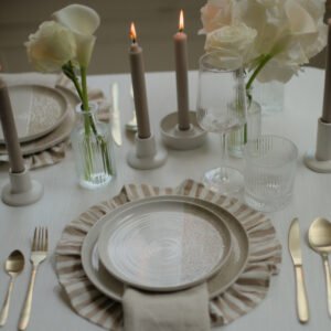 Wit-beige dinerbord in tafelsetting Wit-beige dinerbord op een tafel met bloemen en kaarsen