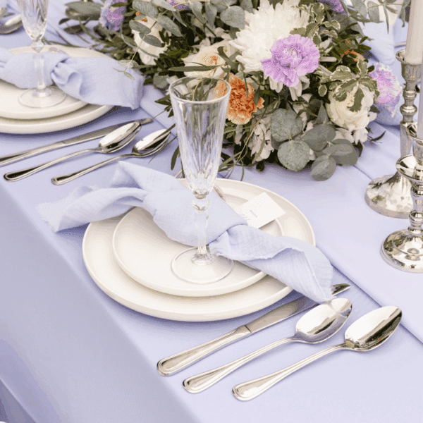 Tafelstyling met zilverlook bestek, witte servetten en bloemstuk in pastelkleuren. Zilverlook bestek met witte servetten en bloemendecoratie
