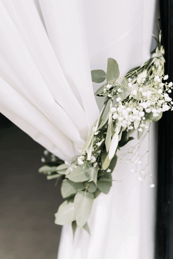 Detail van witte doeken met eucalyptus – elegante styling van entree bij bruiloftslocatie