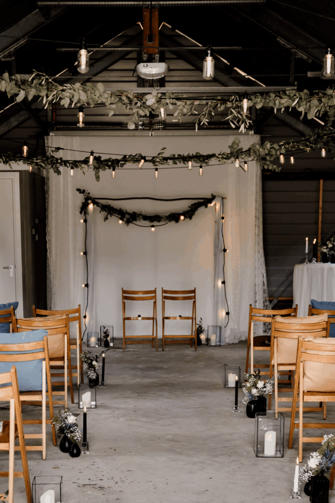 Aankleding van trouwceremonie in oude schuur – rustieke stoelen, doeken en styling die klopt