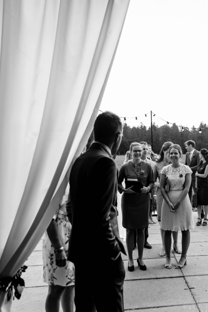 Sfeer creëren op je bruiloft: gasten lopen via witte doeken de gestylde schuur binnen