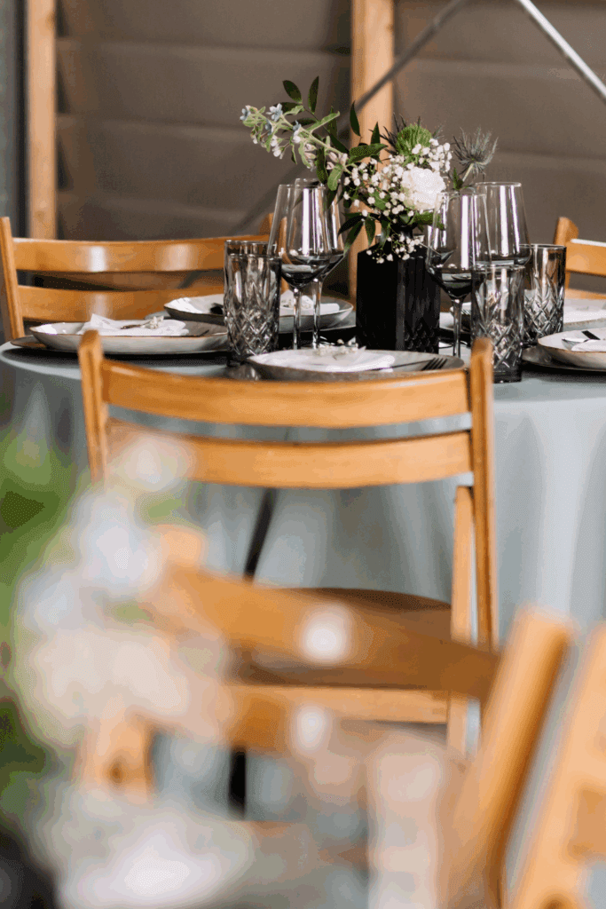 Tafelstyling met donker glaswerk en bloemen op olijfgroen linnen – intieme sfeer en warm kleurcontrast