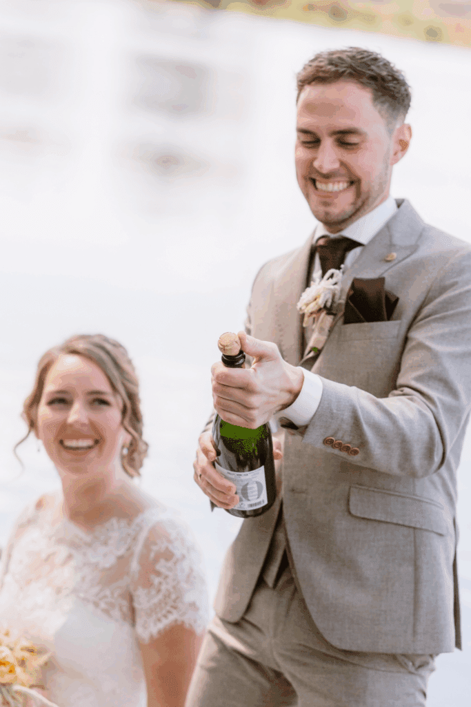 Bruid en bruidegom openen champagne – feestelijk moment op stijlvolle bruiloft met oog voor sfeer en budgetkeuzes