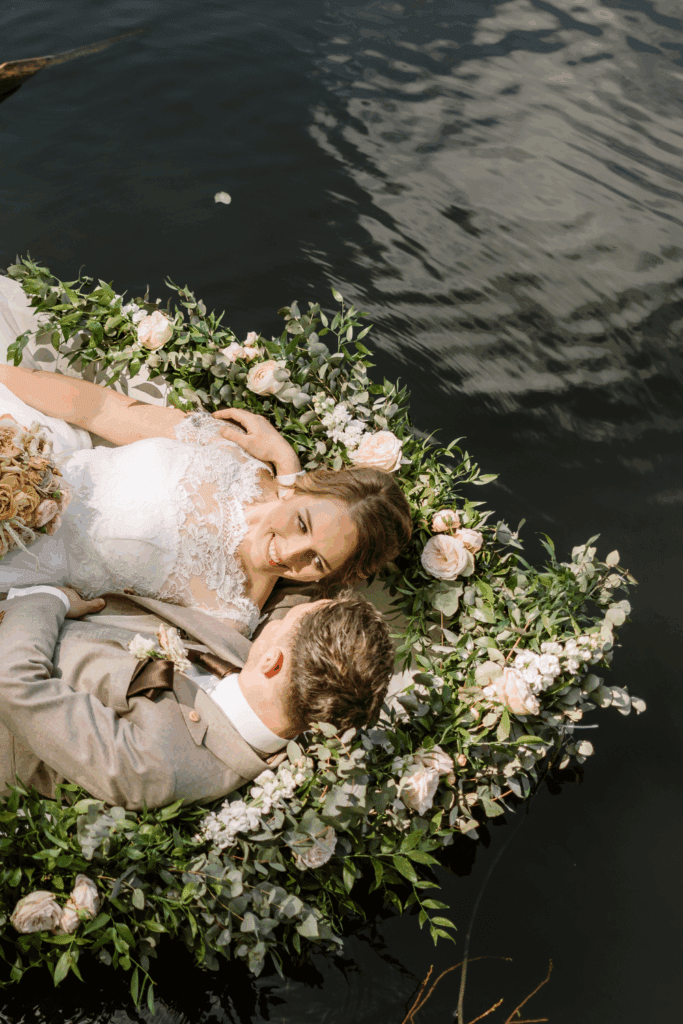 Bruidspaar ontspant samen in roeiboot versierd met bloemen op het water – intieme bruiloft waar sfeer belangrijker is dan budget
