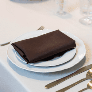bruine servet op stapel borden met goud bestek voor bruiloft of diner