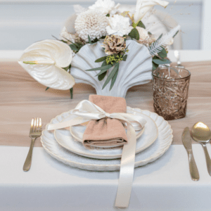 Gedekte bruiloft tafel met beige lunchbordje, linnen servet en goud bestek