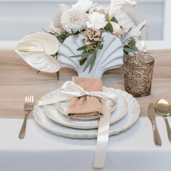Beige lunchbordje in stijlvolle bruiloft tafelsetting met goud bestek Gedekte bruiloft tafel met beige lunchbordje, linnen servet en goud bestek