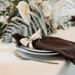 bruine servet op bord met bloemen en servies voor romantische bruiloft tafel