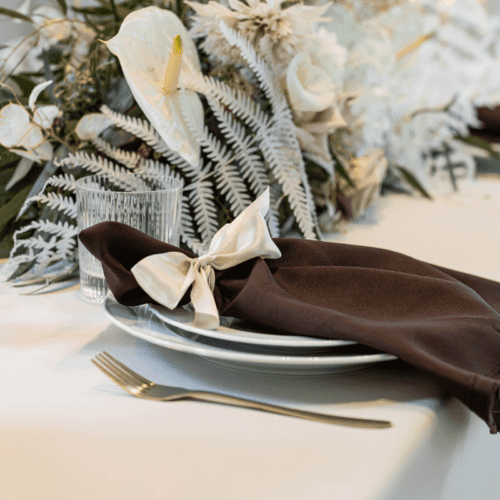 bruine servet op bord met bloemen en servies voor romantische bruiloft tafel