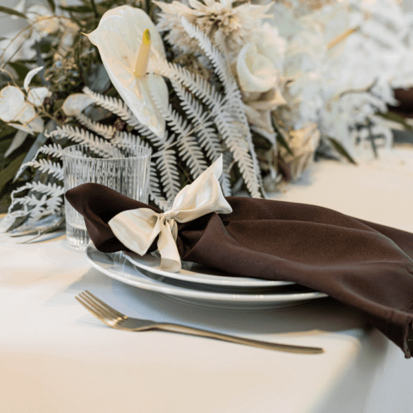 bruine servet op bord met bloemen en servies voor romantische bruiloft tafel