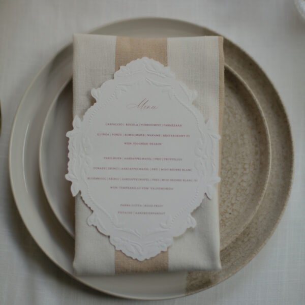Wit-beige gestreepte servet met menukaart Wit-beige gestreepte stoffen servet op een bord met een witte menukaart.