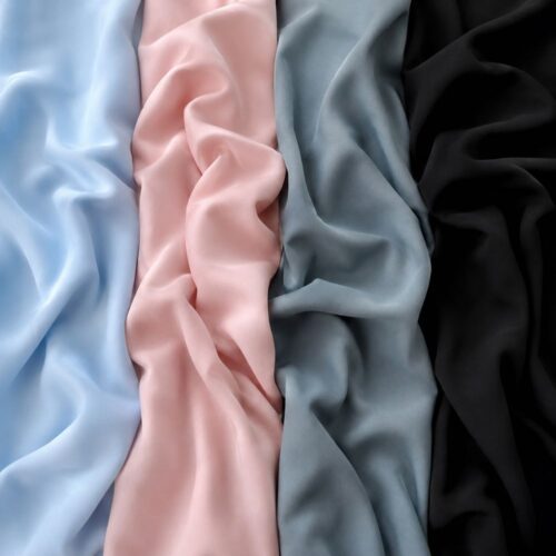 Verschillende kleuren outlet stof voor tafelkleden, decoratie en bruiloftstyling met lichtblauw, zachtroze, blauwgrijs en zwart.