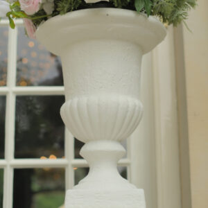 Detail van een klassieke witte vaas Detail van de brede bovenrand en geribbelde onderzijde van een witte vaas op voet.