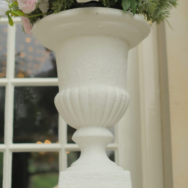 Detail van een klassieke witte vaas Detail van de brede bovenrand en geribbelde onderzijde van een witte vaas op voet.