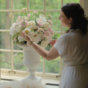 Grote witte vazen huren voor een bruiloft | Feline Styling Grote witte vazen op voet, gevuld met witte en lichtroze bloemen op witte sokkels.