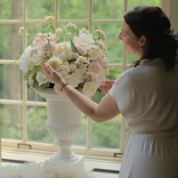 Grote witte vazen huren voor een bruiloft | Feline Styling Grote witte vazen op voet, gevuld met witte en lichtroze bloemen op witte sokkels.
