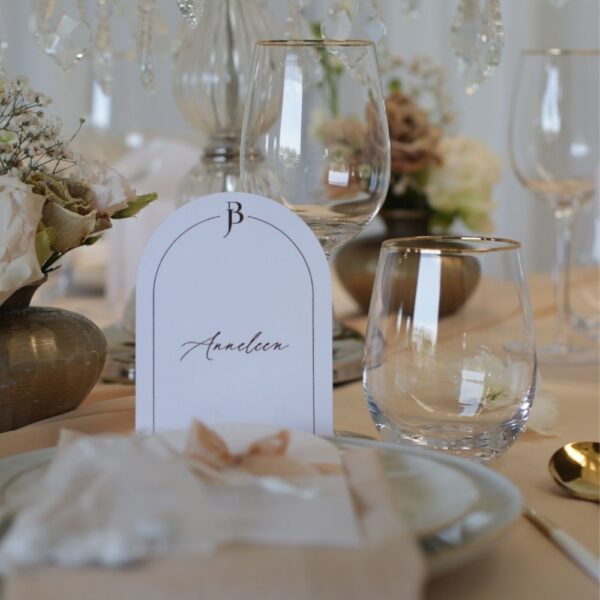 Naamkaart en waterglas met gouden rand op bruiloft