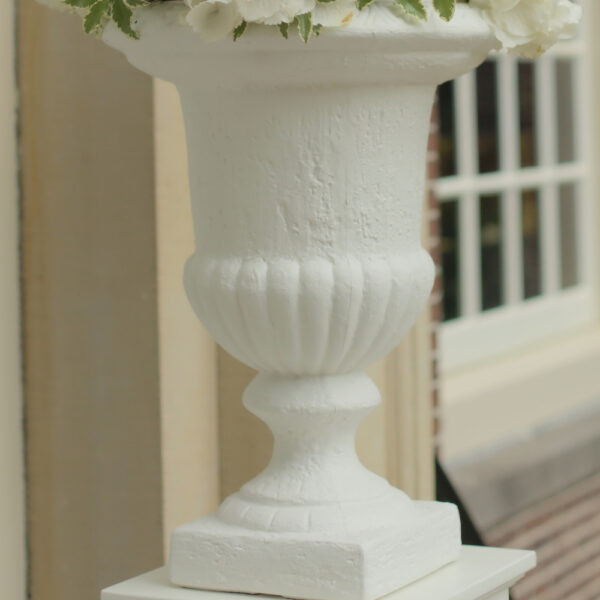 Witte vaas op voet met reliëf Detail van een witte vaas met een gladde kom, geribbelde onderzijde en ronde voet.