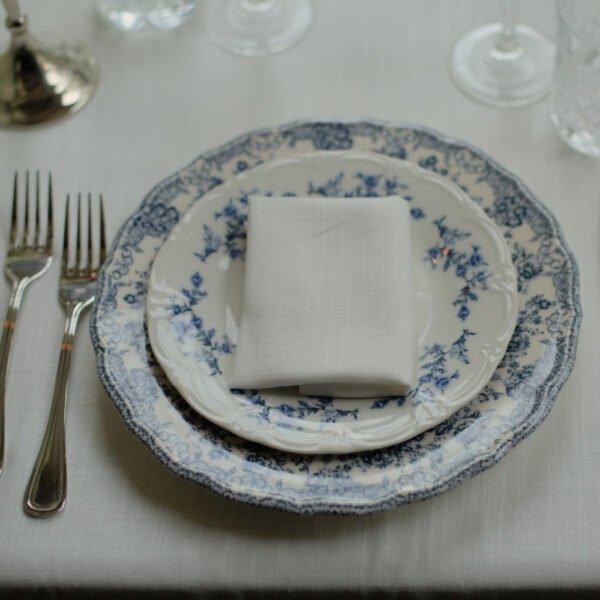 Franse tafelstyling met blauw-wit servies Klassiek porseleinen dinerbord met blauwe bloemen in Franse stijl, gecombineerd met linnen servetten.