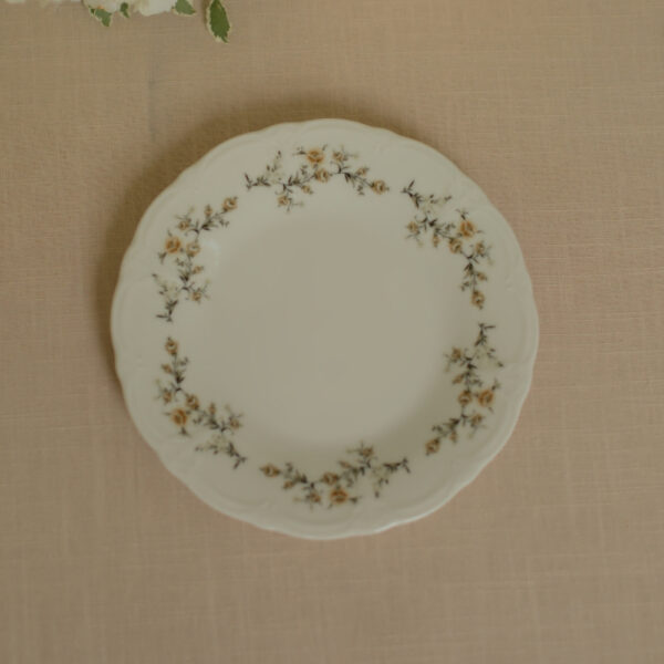 Wit porseleinen dinerbord met bloemenrand in crème, beige, bruin en donkergroen.