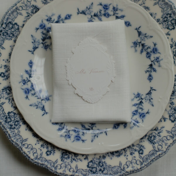Bord met blauwe bloemen voor een gedekte feesttafel Bovenaanzicht van een bord met blauwe bloemen en een wit servet met naamkaartje