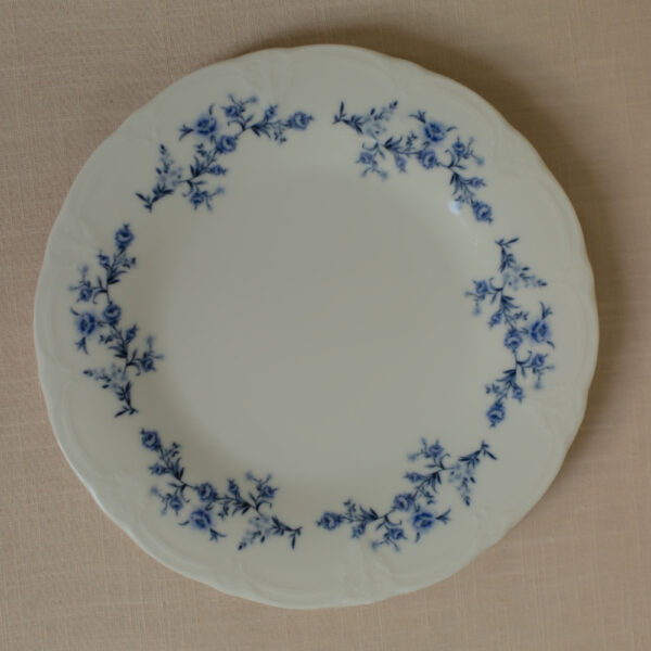Detail van de blauwe bloemen langs de golvende rand van een wit bord